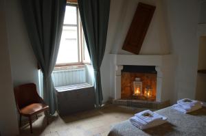 LettopalenaDimora Barbolani的一间卧室设有壁炉、一张床和一把椅子