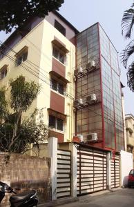 加尔各答Soukyam Hotel的前方停放摩托车的玻璃外墙建筑