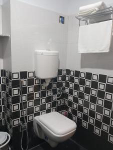 加尔各答Soukyam Hotel的浴室设有卫生间,铺有黑白瓷砖。