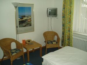 新明斯特弗里德里希酒店的一间带床和两把椅子的房间以及一台电视
