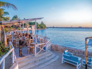达累斯萨拉姆Coral Beach Hotel Dar Es Salaam的一群人坐在水边的餐厅里