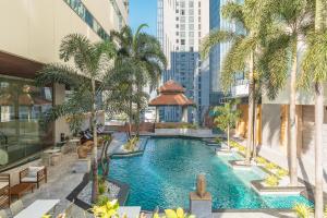 曼谷茉莉城市酒店 (Jasmine City Hotel Bangkok)的一座棕榈树建筑中的无边泳池