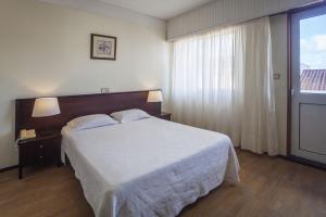 蓬塔德尔加达Hotel Sete Cidades的卧室设有一张白色大床和一扇窗户。