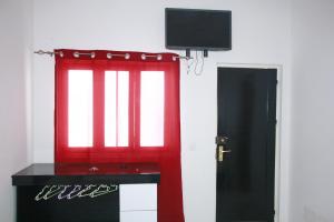 埃斯帕戈斯Académico do Sal的客房设有红色窗户和电视。