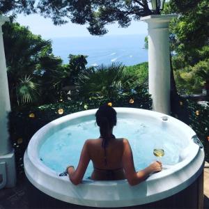 卡普里Villacore Luxury Guest House的坐在按摩浴缸中的女士,看着大海