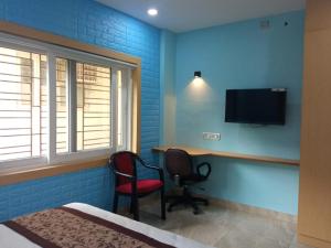 加尔各答Soukyam Hotel的客房设有床、书桌和电视。