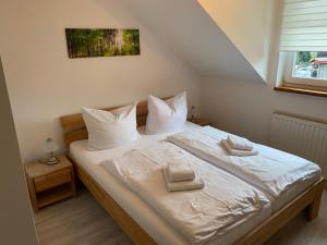 施尔奇Hotel Garni und Gaststätte Zum Holzfäller的一间卧室配有带白色床单和枕头的床。