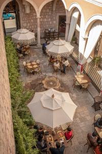 莫雷利亚Casa Vieja Hotel Boutique的享有带桌子和遮阳伞的天井的顶部景致。