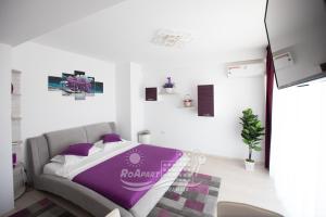 马马亚RoApart Mamaia - Riva Lake Apartments的白色客房内的一间卧室配有一张紫色的床