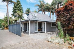 陶朗加Te Puna Cottage Gardens B&B的白色的房子,有围栏和棕榈树