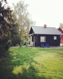 KärdeSelf Check-in Sauna Cabin next to Hiking Trails的院子里有两把蓝色椅子的黑色房子