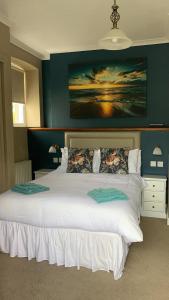 库姆马丁The Poplars Guest House的卧室配有一张白色大床,墙上挂有绘画作品