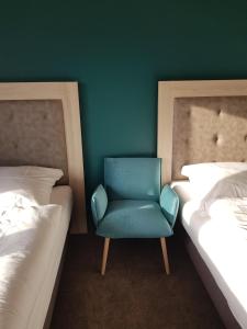 埃姆登Boardinghouse am Borkumkai的一张蓝色椅子,坐在房间两张床之间