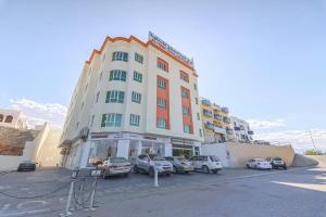 苏尔Super OYO 111 Al Thabit Hotel的停车场内停放汽车的大型建筑