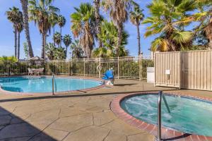 亨廷顿海滩Comfort Inn & Suites Huntington Beach的一个带围栏和棕榈树的游泳池