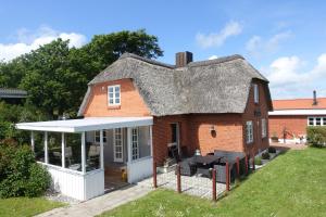 斯楚厄Thatched Holiday Home in Struer, Jutland with a view的一座带茅草屋顶和庭院的古老房屋