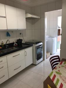 大普拉亚Apto super confortável 1 quadra da praia Wi-Fi 02 banheiros Churrasqueira na sacada的厨房配有白色橱柜、炉灶和冰箱。
