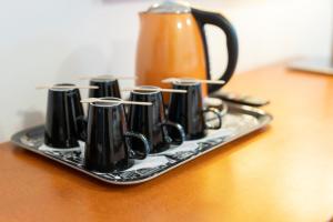 TuulosHotel Tuulonen的茶壶,桌子上装有黑杯的托盘