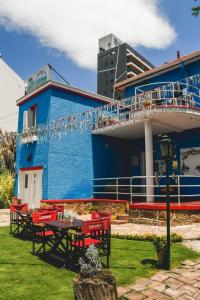 维拉卡洛斯帕兹Blau Hostel的蓝色的建筑,配有红色的椅子和桌子