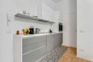 米兰New Milan Central Apartment的厨房配有白色橱柜和厨房地毯。
