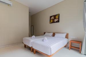 新加拉惹Josh Guest House的卧室配有白色的床和2条毛巾