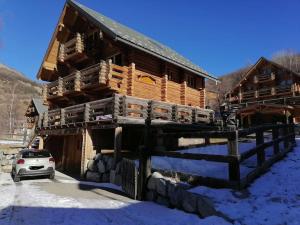 阿洛斯Chalet Les Pins Blancs的雪地里的小木屋,前面有停车位