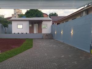 伊茹伊Trentino 66 - Hospedagem em Ijuí, casa agradável com estacionamento的白色的房子,有栅栏和砖车道