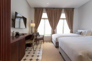 金边La Chronique Hotel的酒店客房配有两张床和一张书桌