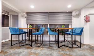 那格浦尔Treebo Trend Finesta Suites, Nagpur Airport的一间设有蓝色桌椅和窗户的用餐室