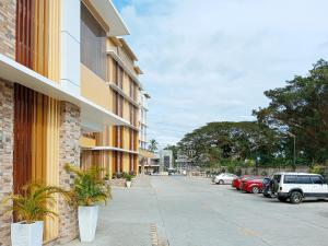 达沃市Sans Hotel at The Luxebridge Suites Davao的一条街道,汽车停在大楼的一侧