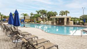 基西米Townhome w pool near Disney & Orlando Attractions的度假村内带椅子和遮阳伞的游泳池