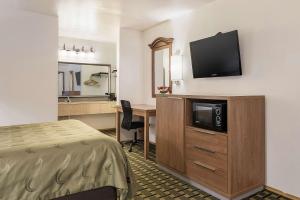 金城Quality Inn Near Fort Hunter Liggett的酒店客房配有一张床和一张书桌及一台电视
