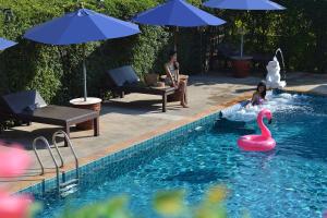素可泰Thai Thai Sukhothai Resort的几个人在游泳池里,有粉红色天鹅