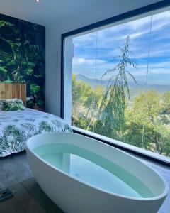 Torrelles de Llobregat佩蒂特米拉多酒店的卧室设有浴缸,卧室设有大窗户
