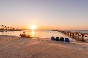 赫尔格达Pickalbatros Palace - Aqua Park Hurghada的日落时在海滩上冲浪板