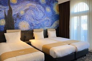 阿姆斯特丹Hotel Van Gogh的墙上画画的房间里设有两张床