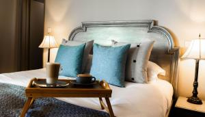 潘本大象酒店的一张带蓝色枕头的床和一个带杯子的托盘