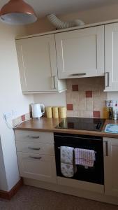 坎贝尔城Modern 1 bed Apartment close to Campbeltown的厨房配有白色橱柜和炉灶烤箱。