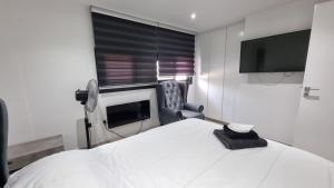 卡科佩特里亚Nagia’s Apartment的一间卧室配有一张床、一台电视和一把椅子