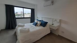 罗萨里奥Suites Quality 2 - Rosario的一间卧室配有一张带蓝色枕头的床和一扇窗户。