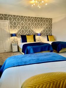 基拉尼奇拉伦屋酒店的一间卧室配有3张带蓝色和黄色枕头的床