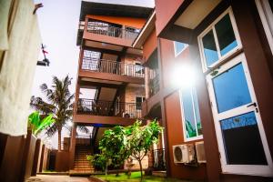 库马西Homey Lodge的公寓大楼设有阳台和棕榈树