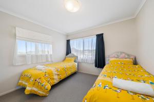 Oroua DownsHunia Haven - Himatangi Beach Holiday Home的卧室内的两张床,配有黄色床单