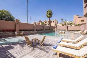 马拉喀什艾优步Spa酒店的一个带椅子的庭院和一个带桌子的游泳池