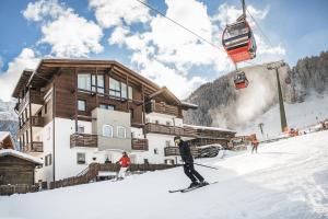 塞尔瓦迪加尔代纳山谷Garni Hotel Miara - Your Dolomites Home的滑雪者在滑雪缆车前的雪中滑雪