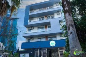 古尔冈Lime Tree Hotel Near 32nd Avenue Sector 29 Gurgaon的前面有棵树的蓝色建筑