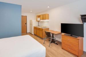 法尔WoodSpring Suites Pharr的酒店客房配有一张床、一张书桌和一台平面电视