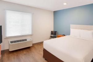 法尔WoodSpring Suites Pharr的卧室配有白色的床和窗户。