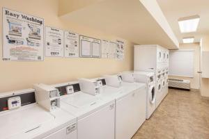 布朗斯维尔WoodSpring Suites Brownsville的洗衣房配有白色家电和墙上的标志