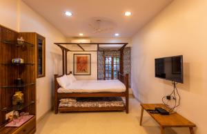 孟买SaffronStays Birdsong, Madh - pet-friendly villa at Madh Island的一间卧室配有一张床和一台电视。